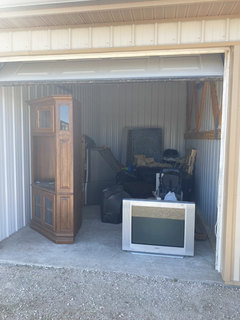 Storage unit with old furniture and TV before cleanout